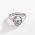 Chunky silver-tone open ring with a large oval clear faceted stone set flush in a thick border and a wavy melted texture.