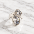 Chunky silver-tone open ring with a hammered texture and two large clear oval faceted stones set diagonally.