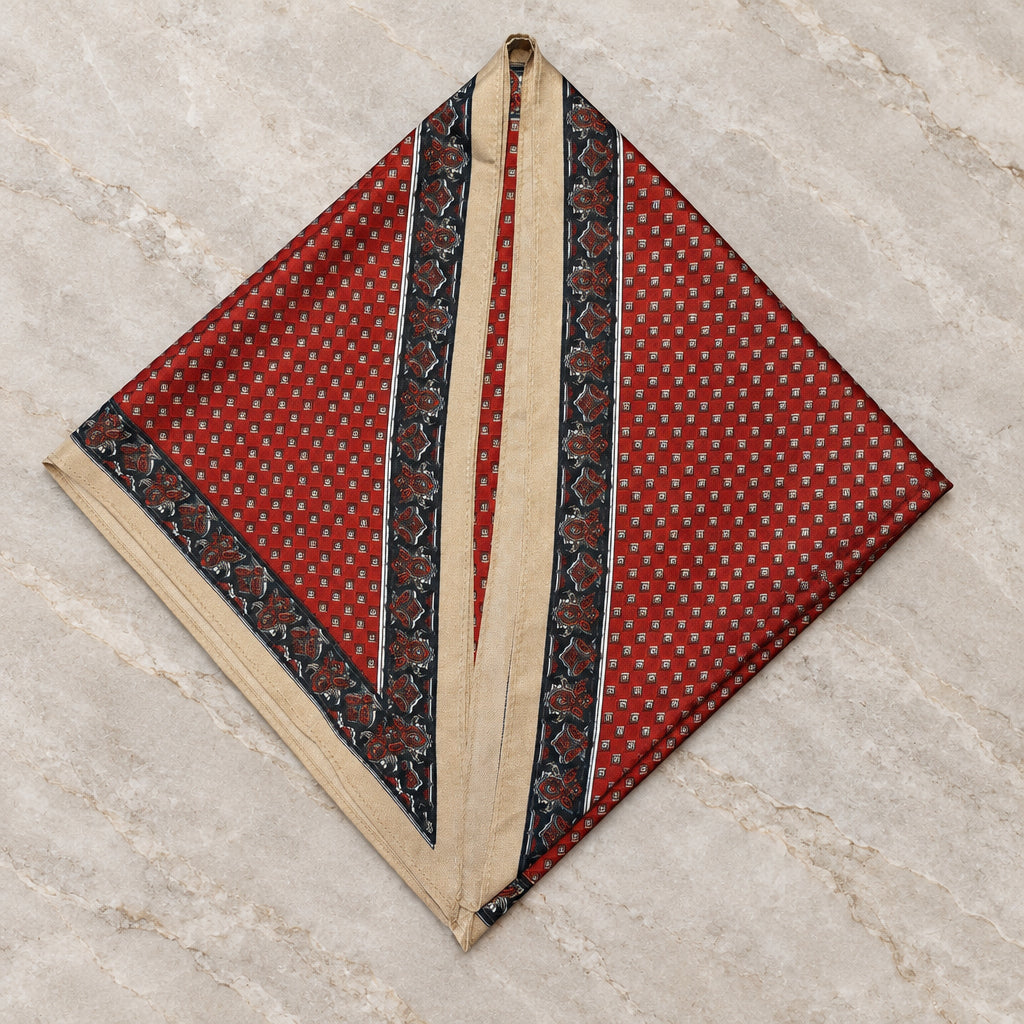 Rust Revival Triangle Scarf in rust red twill, folded into a point on gray marble with black and cream borders