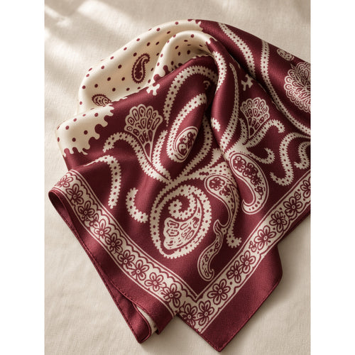 Burgundy and cream paisley square scarf loosely folded on a cream linen surface