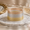 Stack of nine champagne glitter jelly bangles on a marble tray with a gold mirror