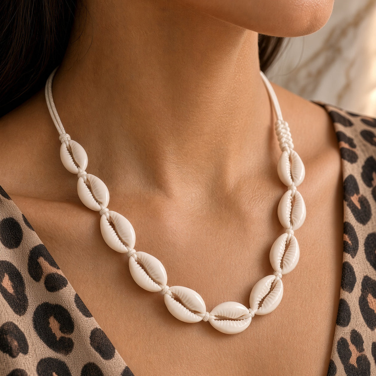 Woman wearing white cowrie shell necklace on ivory cord with a leopard print top