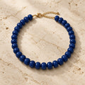 Chunky navy blue acrylic bead necklace with gold-tone clasp on white and gold marble with champagne satin.