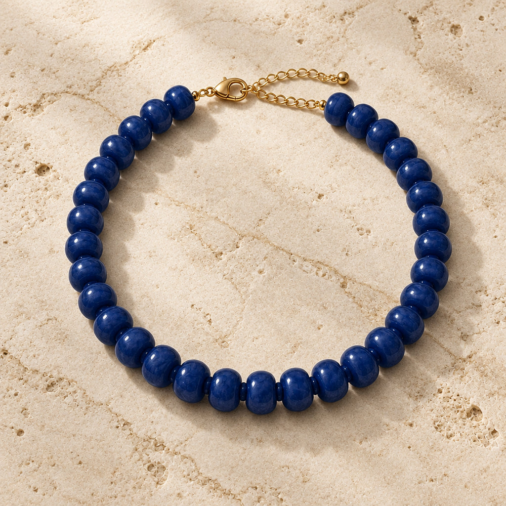 Chunky navy blue acrylic bead necklace with gold-tone clasp on white and gold marble with champagne satin.