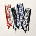 Four paisley twilly scarves in rust, black with white border, navy and black on white marble.