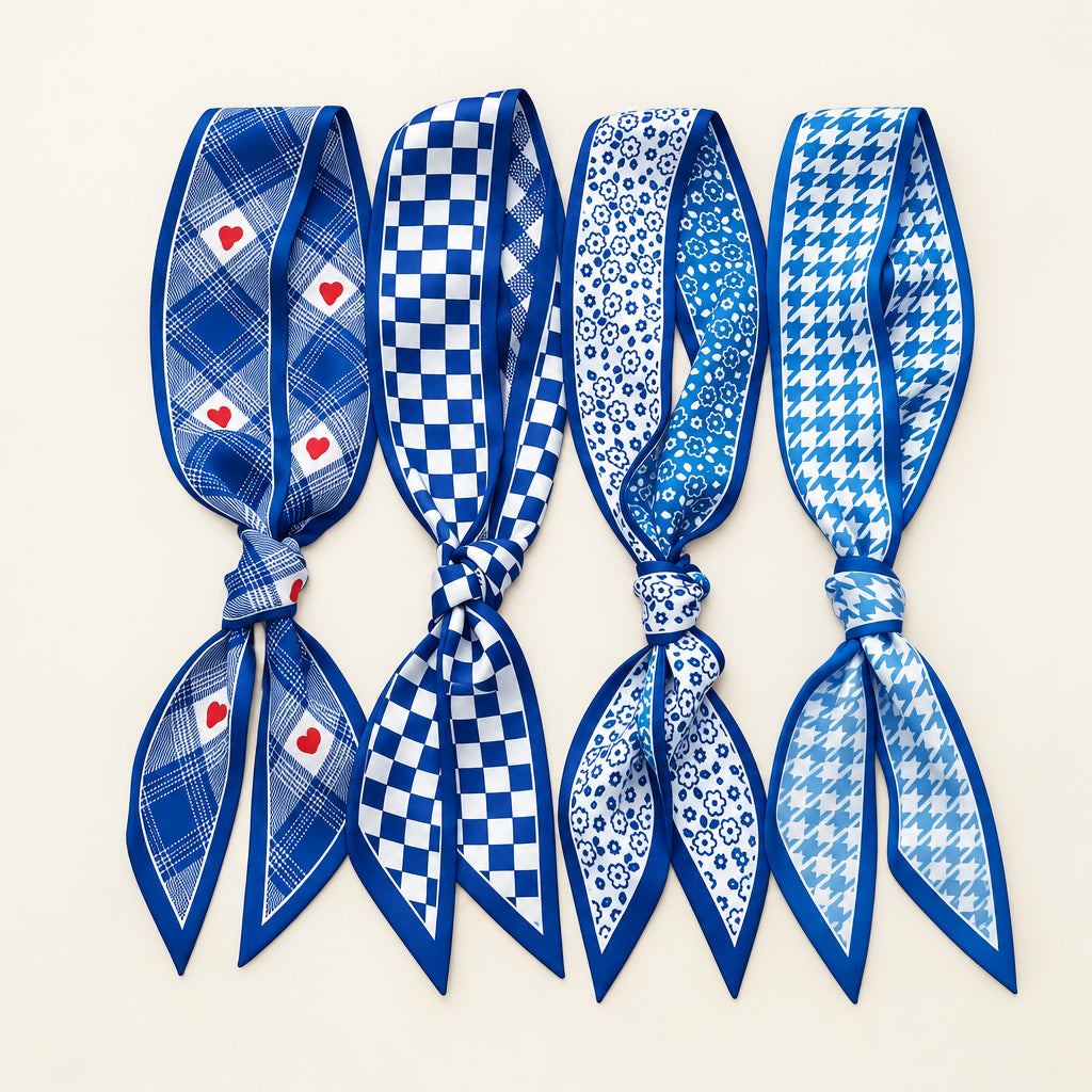 Four blue and white twilly scarves in heart plaid, checkerboard, floral and houndstooth prints on white marble.