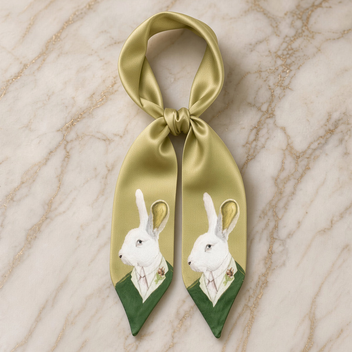 Olive-gold twilly scarf tied in a knot showing twin white hare portraits on marble