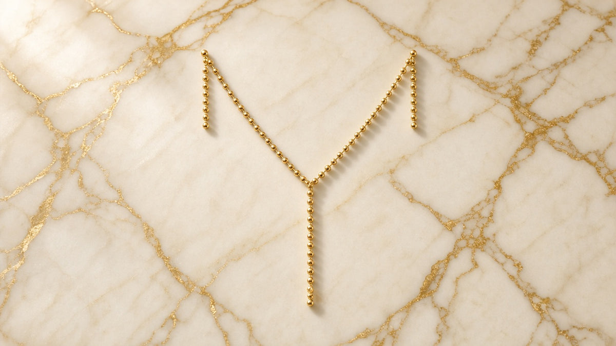Gilded Pearl Drop Lariat on cream marble with gold veining