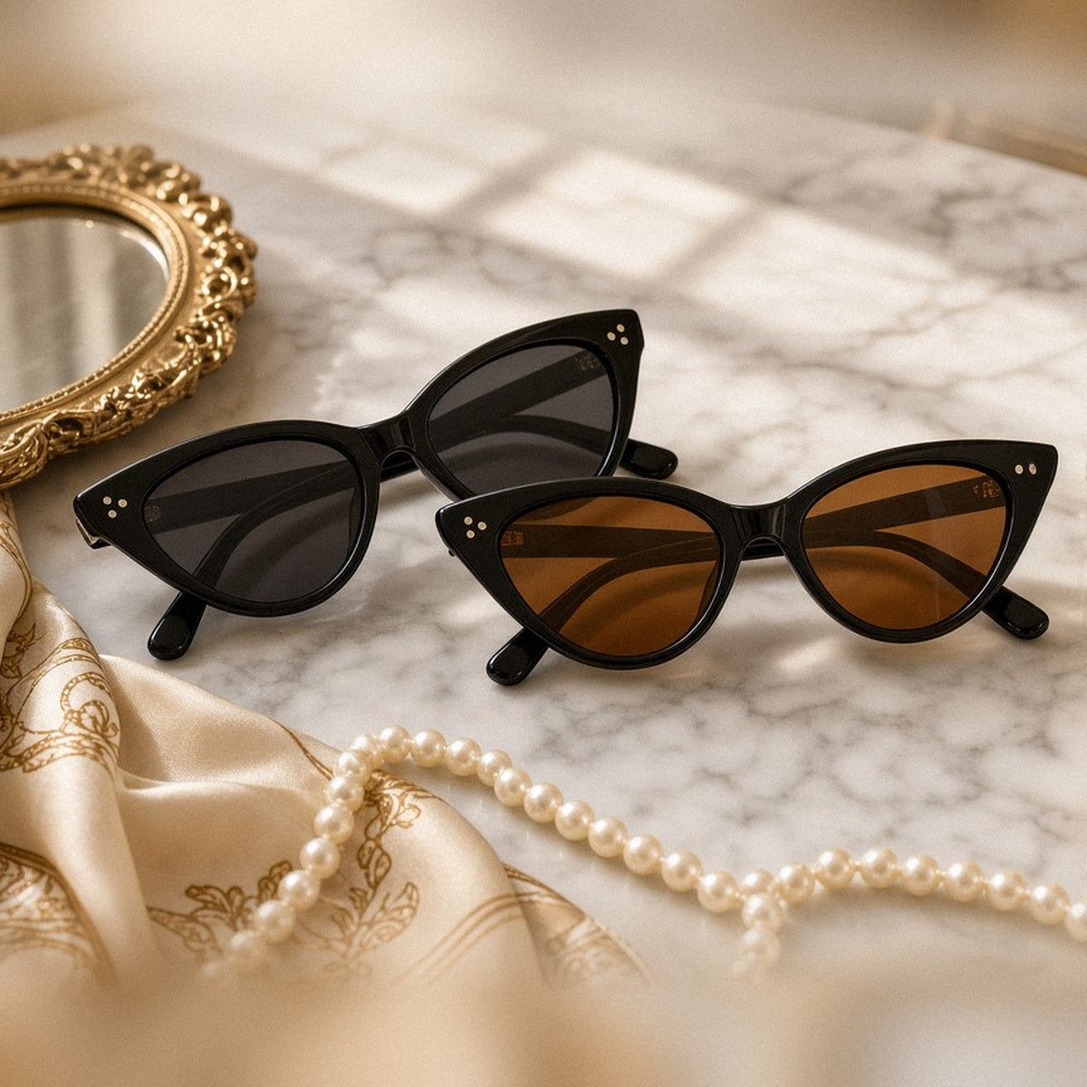 Riviera cat-eye sunglasses in gray and brown lenses on a marble vanity with pearls